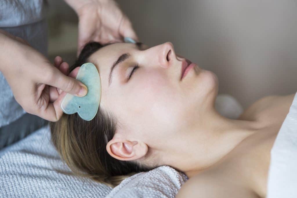 Młoda kobieta doświadcza masażu głowy gua sha